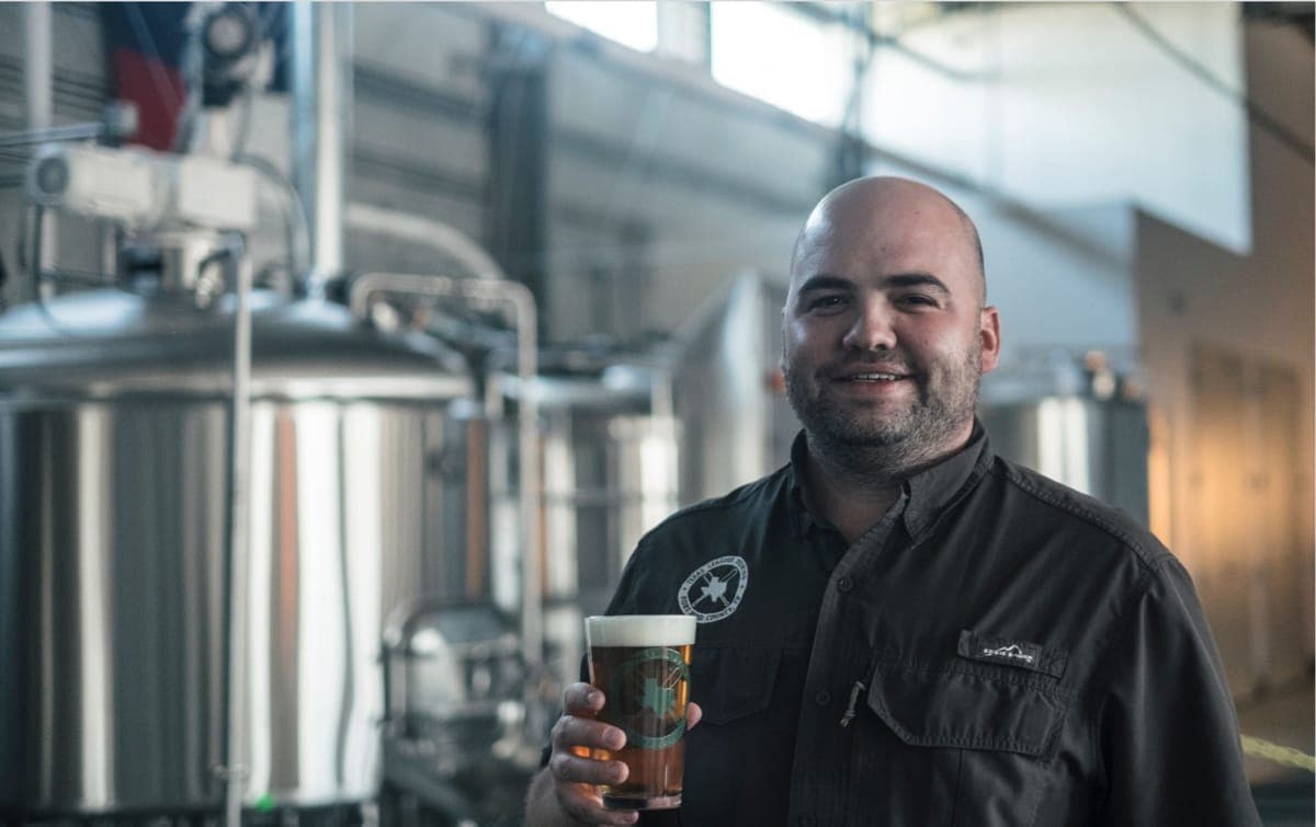 Owner, Nathan Reese holding a pint of beer